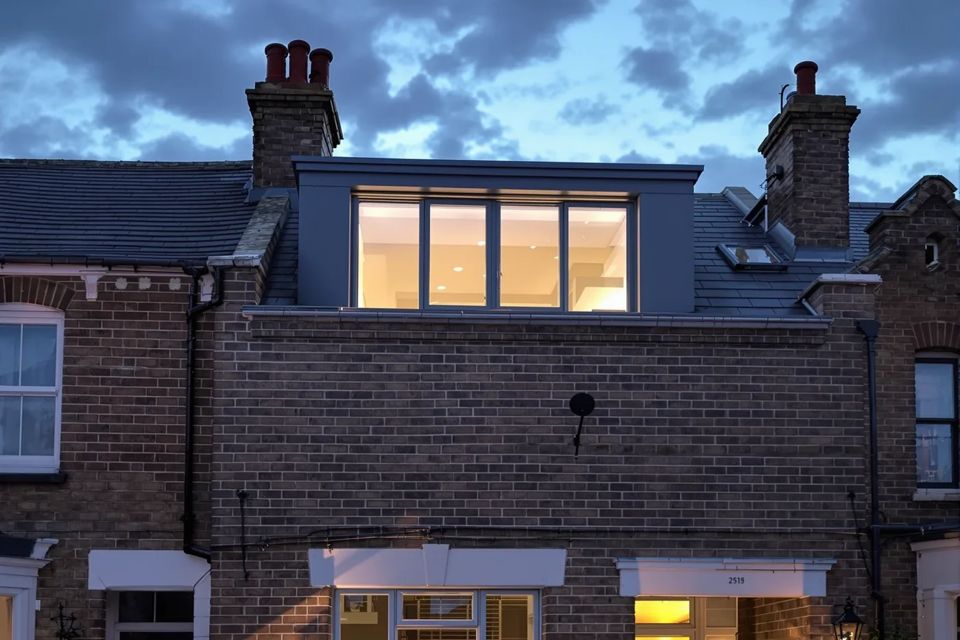 Victorian terrace with completed dormer loft conversion, slate-grey render, precision brickwork, dusk light