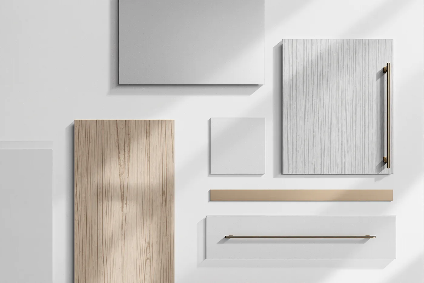 An overhead flat-lay of the studio's material samples laid out in a precise grid on a pale cool-grey surface: honed pale stone, a brushed steel sheet, a cool grey cabinet door, large-format tile, a steel handle and a slim brass hairline strip.